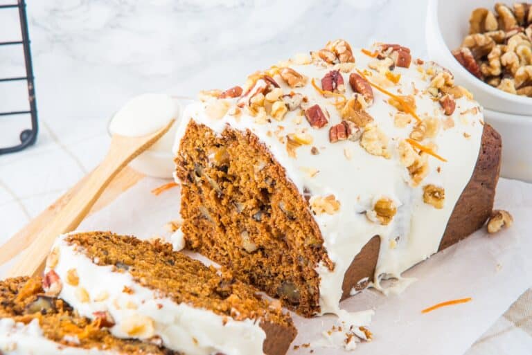 Carrot cake loaf with cream cheese frosting with pieces cut in fan formation.