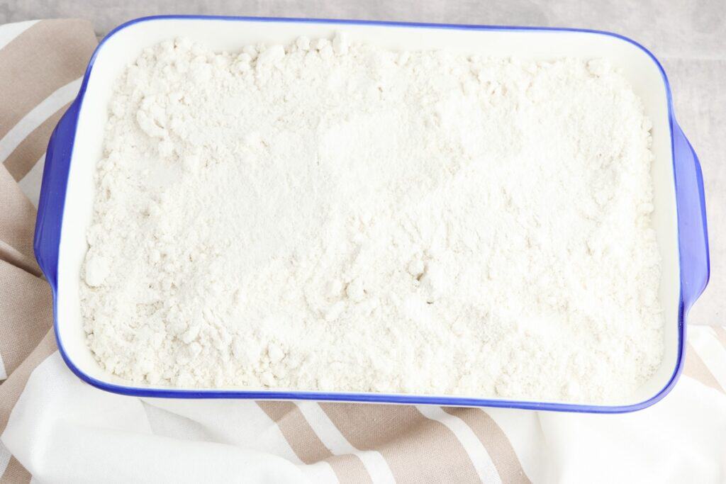 Coffee cake mix and cream cheese icing covering cinnamon roll pieces in baking dish.