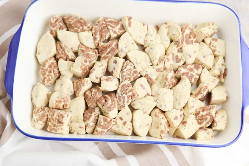 Cinnamon roll pieces in baking dish.