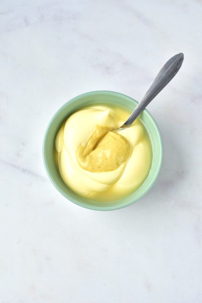 Egg salad in process - mayonnaise and mustard in bowl.