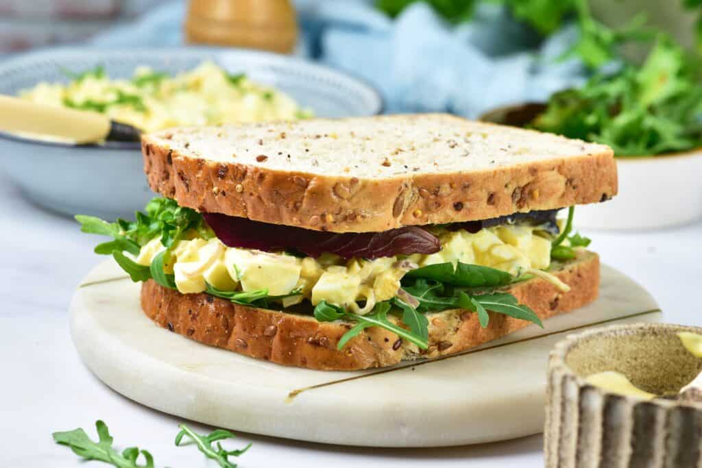 Egg salad sandwich on marble tray.