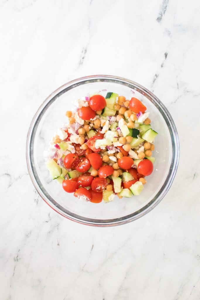 Chickpea Salad vegetable ingredients in glass bowl, overhead shot.