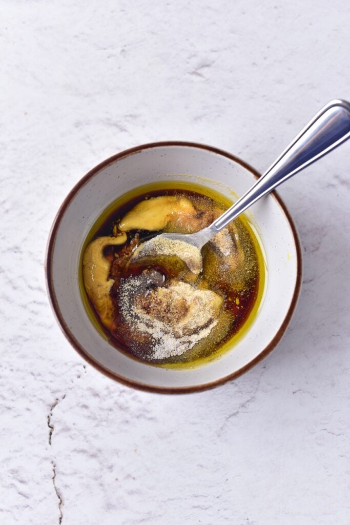 Maple Mustard Glazed Cod marinade ingredients with spoon in small mixing bowl.