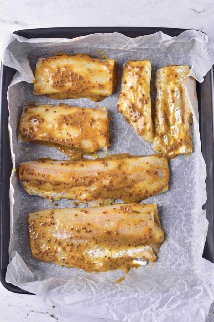 Maple Mustard Glazed Cod, ready to cook, on parchment lined baking pan.