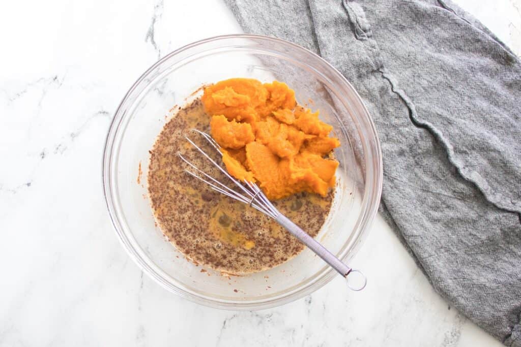 Pumpkin French Toast Bake, in process, batter ingredients whisked with pumpkin puree in glass bowl.