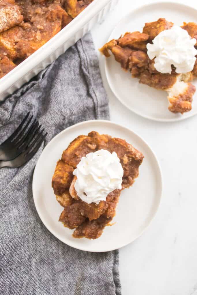 Pumpkin French Toast Bake, piece on small white plate with whipped cream, overhead shot.