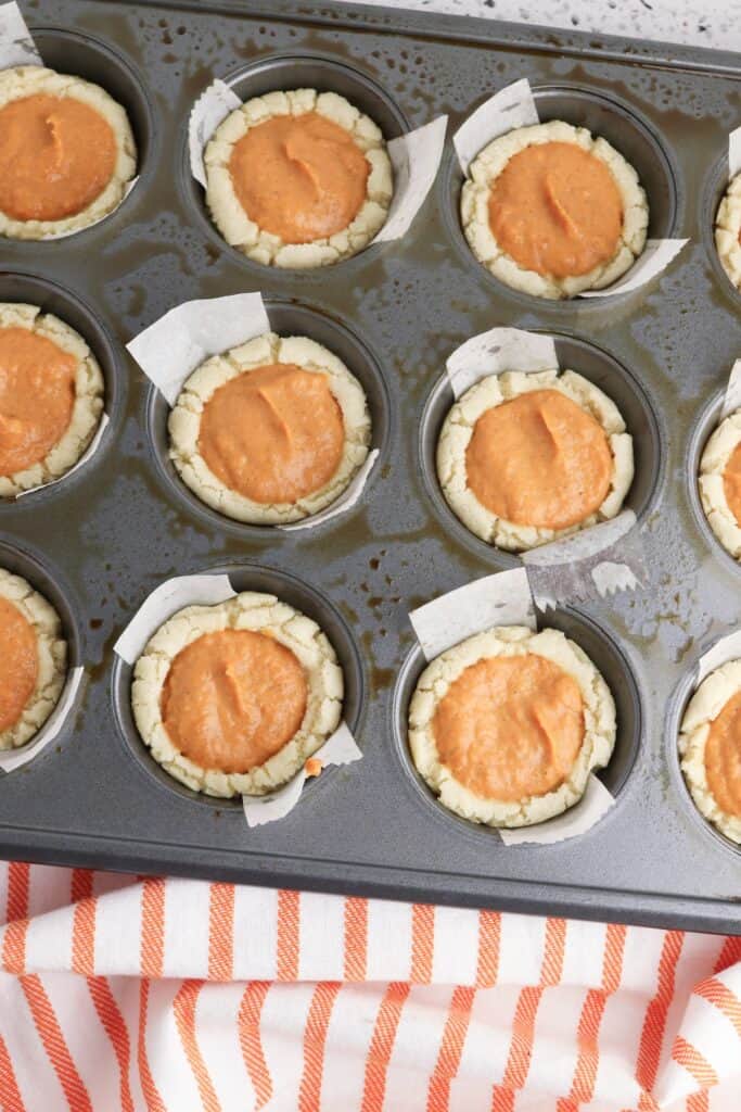 Pumpkin Pie Sugar Cookies, in process, filled cookie dough in parchment lined muffin pan.