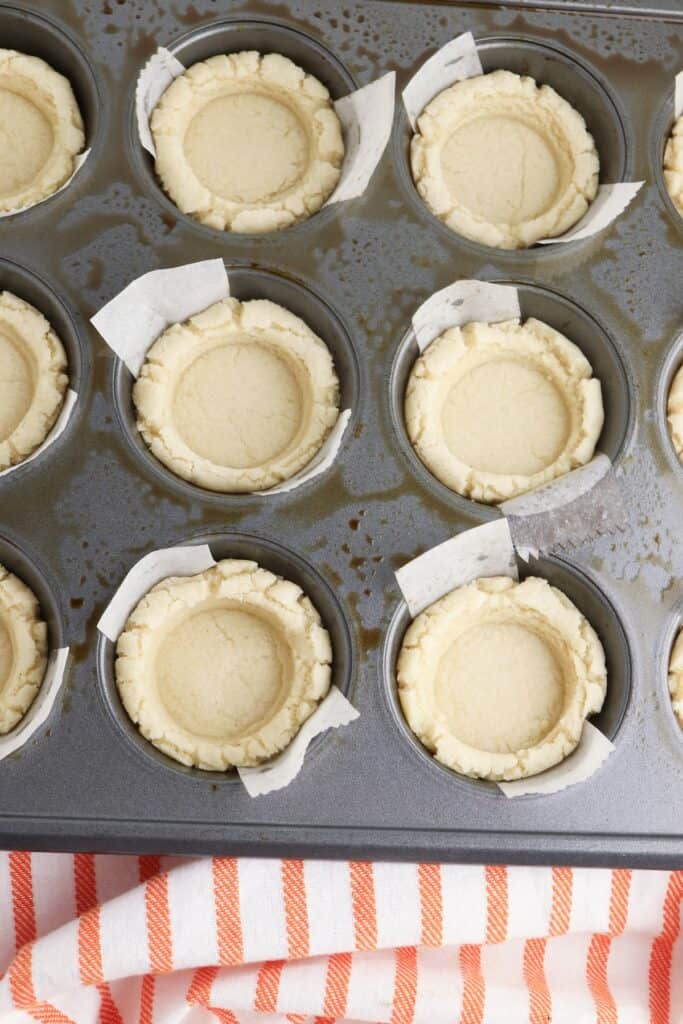 Pumpkin Pie Sugar Cookies, in process, flattened cookie dough in parchment lined muffin pan.