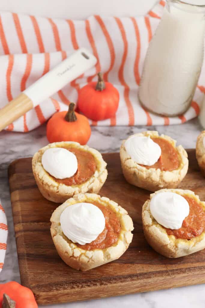 Pumpkin Pie Sugar Cookies on wooden cutting board with striped towel.