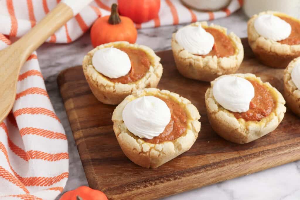 Pumpkin Pie Sugar Cookies on wooden cutting board with striped towel.