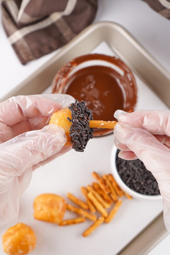 Acorn Donut Holes, in process, attaching pretzel pieces to donut holes.