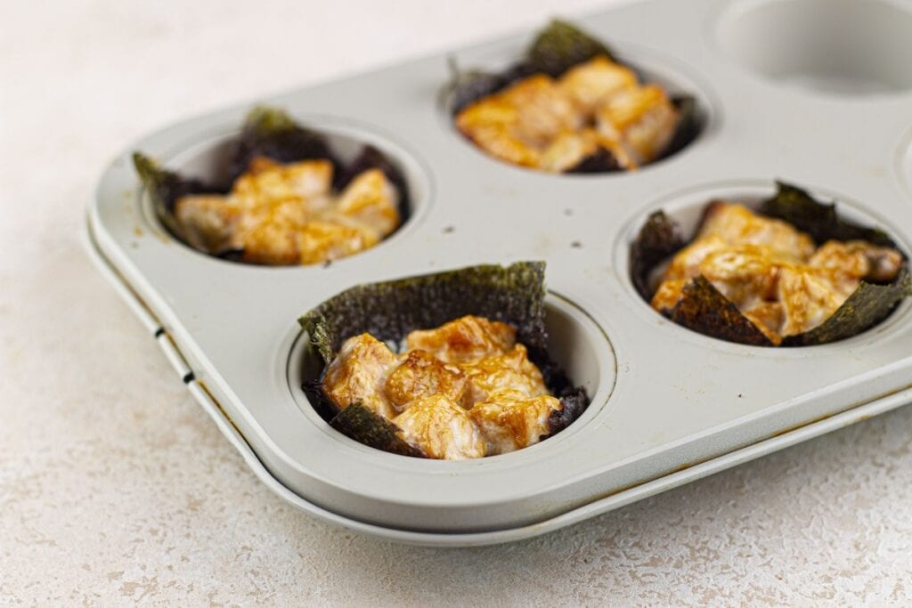 Baked Salmon Sushi Cups, in process, baked nori squares with cauliflower rice and salmon in muffin pan.