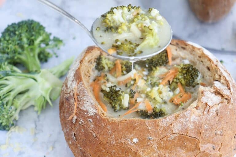 Creamy Broccoli Cheddar Soup, in bread bowl with spoon.