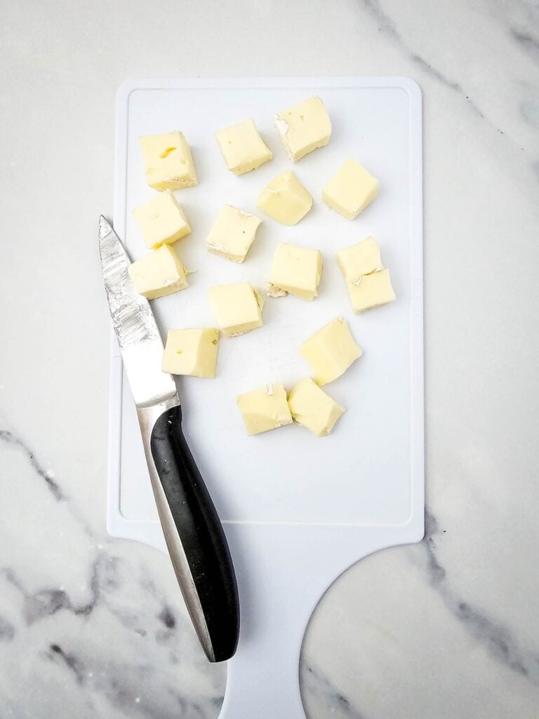 Cranberry and Walnut Brie Bites, in process, cubes on brie on cutting board.
