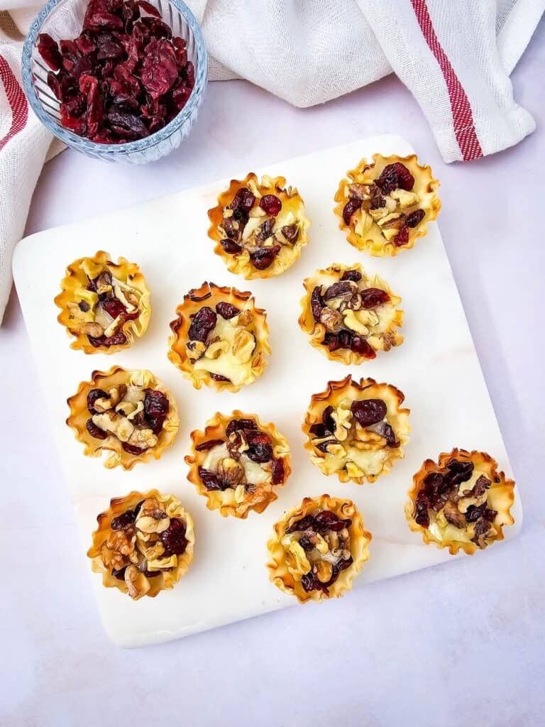 Cranberry and Walnut Brie Bites on white tray, overhead shot.