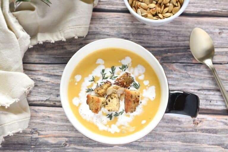 Creamy Butternut Squash Soup in soup bowl, overhead shot on wooden background.