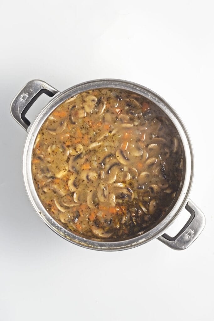Creamy Mushroom Wild Rice Soup, in process, broth and mushrooms added to base of soup.