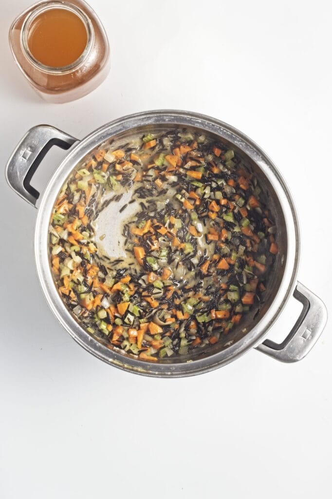 Creamy Mushroom Wild Rice Soup, in process, cooked vegetables and herbs in stock pot.