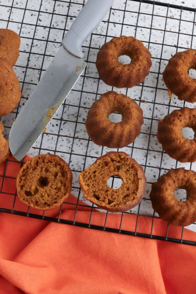 Mini Cream Cheese Pumpkin Cakes, in process, cakes cut in half on cooling rack.