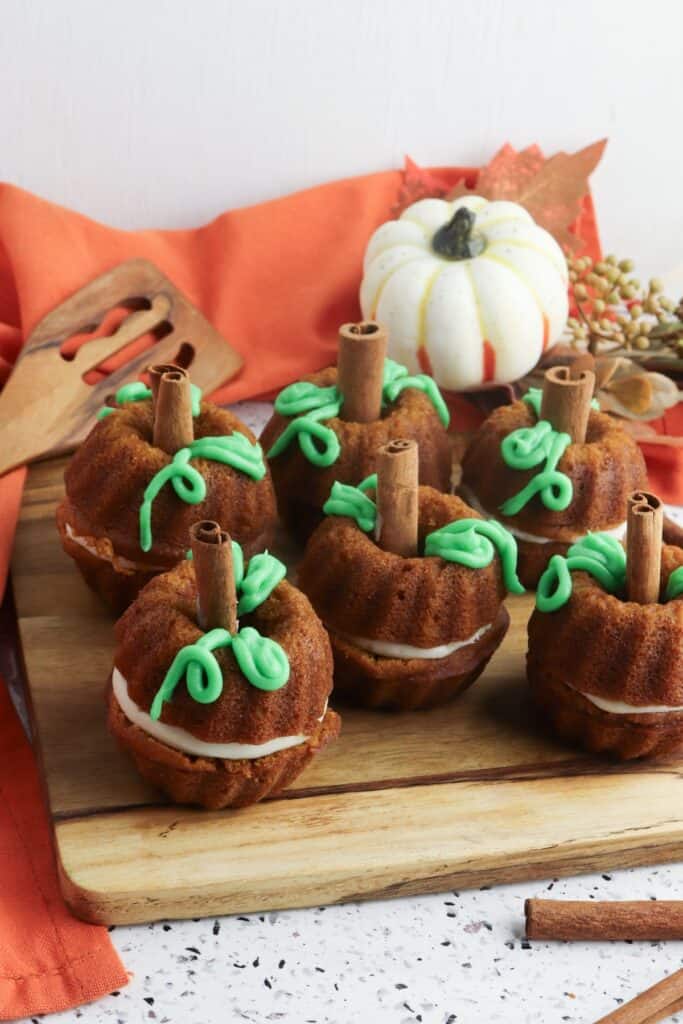 Mini Cream Cheese Pumpkin Cakes on wooden cutting board.