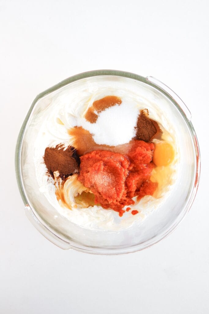 Pumpkin Spice Fudgy Brownies, in process, wet ingredients and spices added to cream cheese in glass mixing bowl.