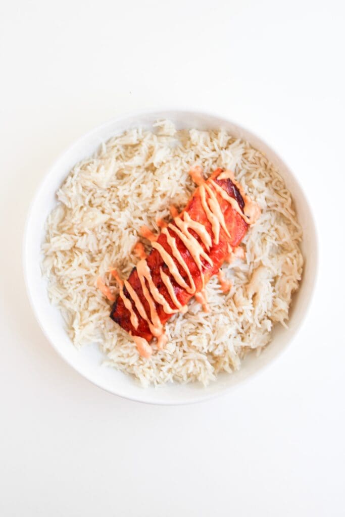 Spicy Salmon Bowl, in process, spicy mayo, salmon, and rice layer in bowl.