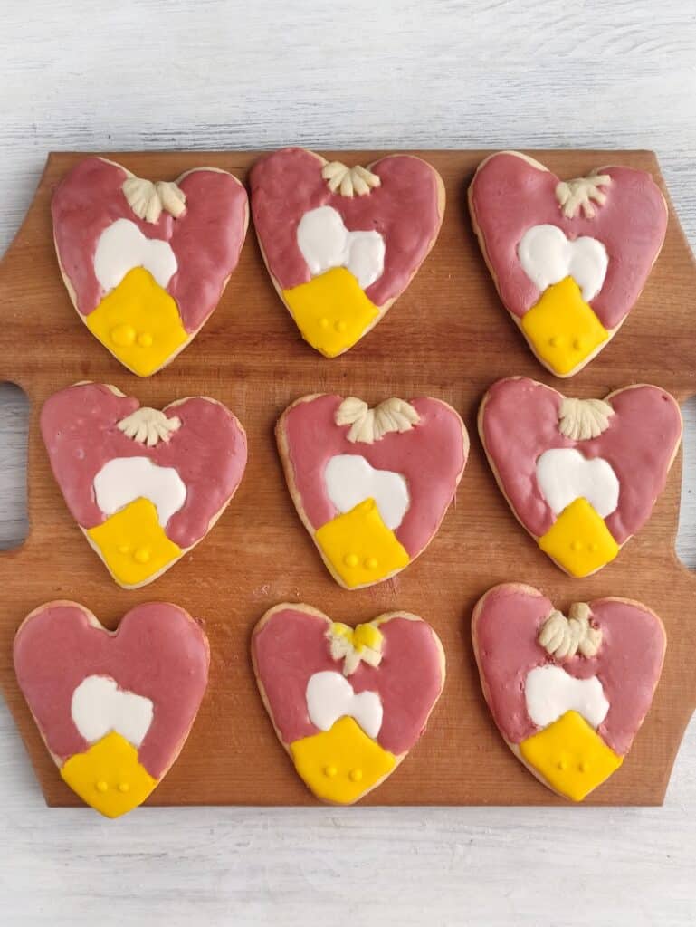 Turkey Sugar Cookies, in process, heart-shaped cookie dough with yellow, white, and dark pink piped onto cookies.