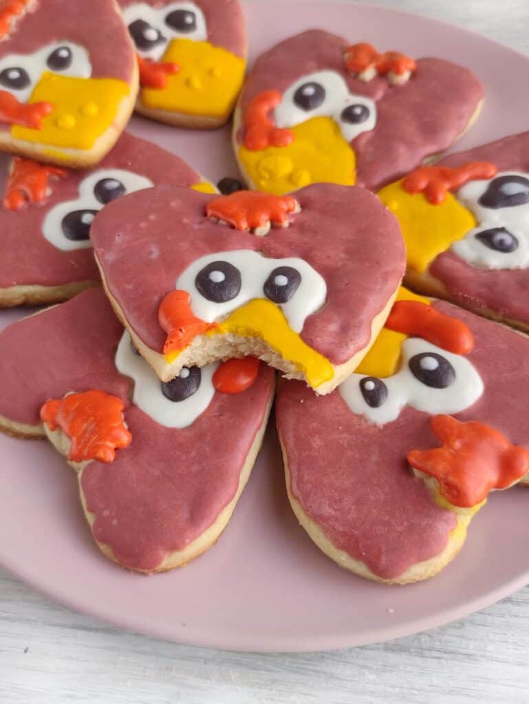 Turkey Sugar Cookies on pink plate with a bite taken from one cookie.
