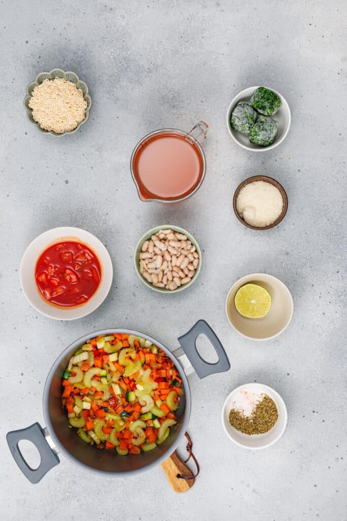 Veggie Minestrone Soup, in process, cooking vegetables in pot with other ingredients on the side.