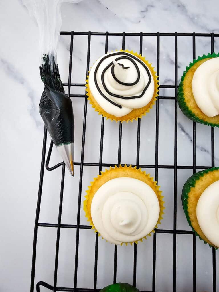 Christmas Light Cupcakes, in process, cupcakes on wire rack with black string lights piped onto the frosting.