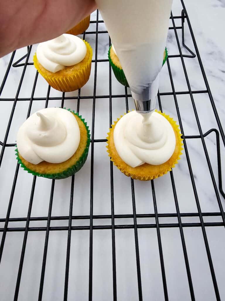 Christmas Light Cupcakes, in process, cupcakes on wire rack with white frosting piped onto cupcake.