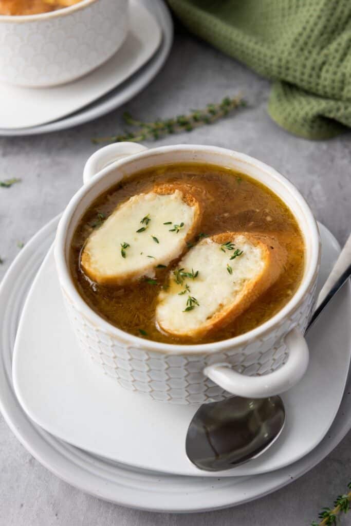 French Onion Soup with cheese baguettes in white soup bowl.