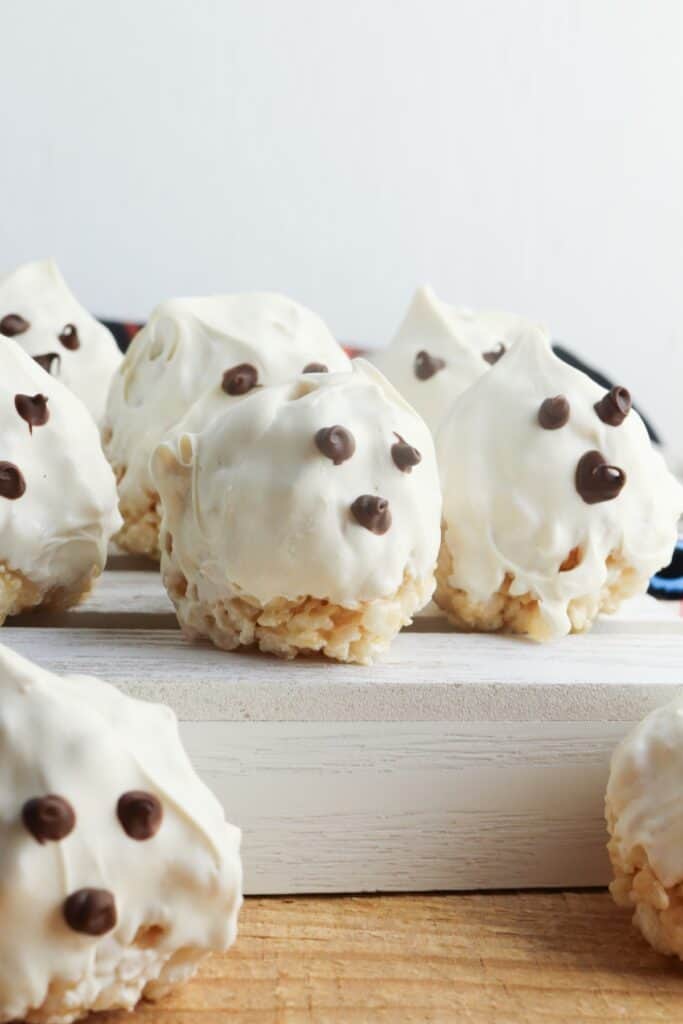 Chocolate-covered Ghost Rice Krispie Treats on wooden stand.