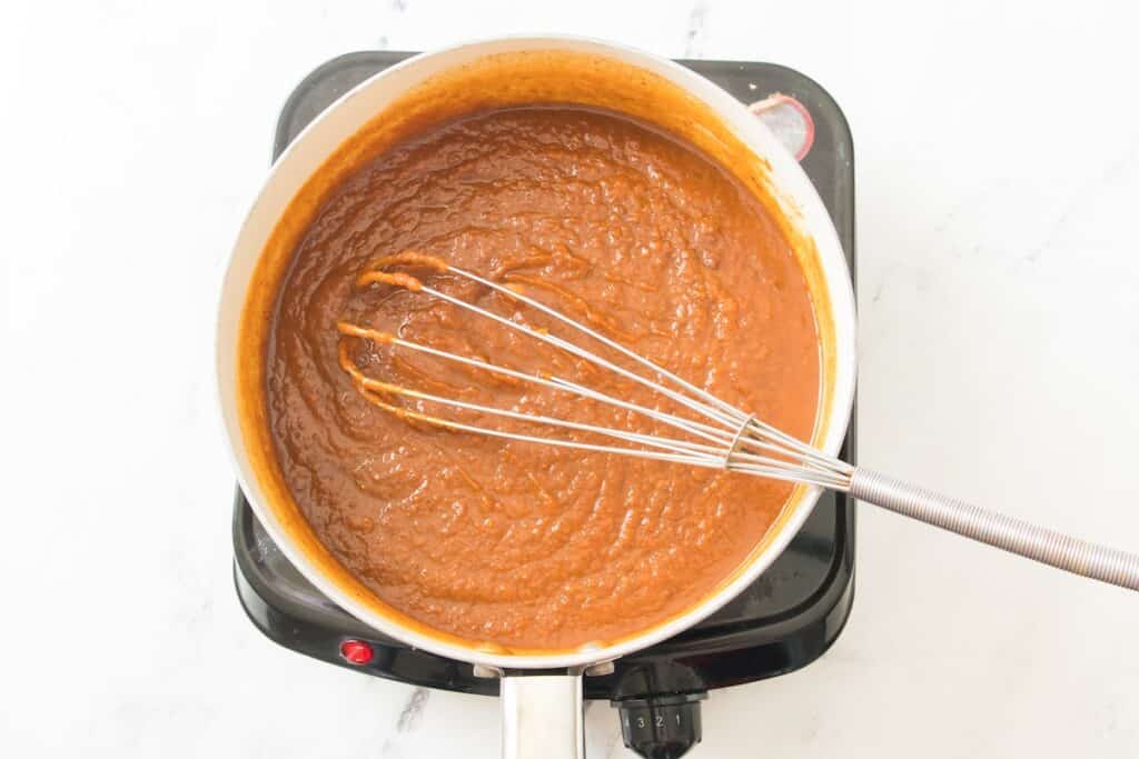 Homemade Pumpkin Butter, in process, stirring ingredients in pot with whisk.
