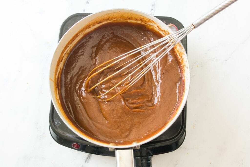 Homemade Pumpkin Butter, in process, stirring ingredients in pot with whisk.