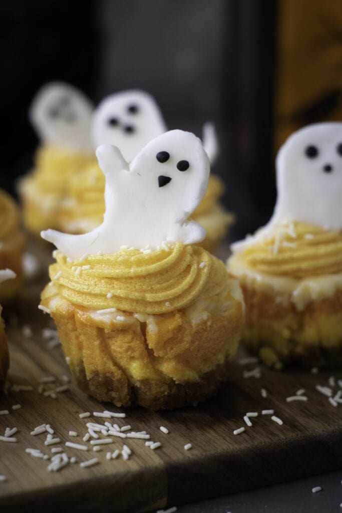 Mini Candy Corn Cheesecakes on wooden chopping block.
