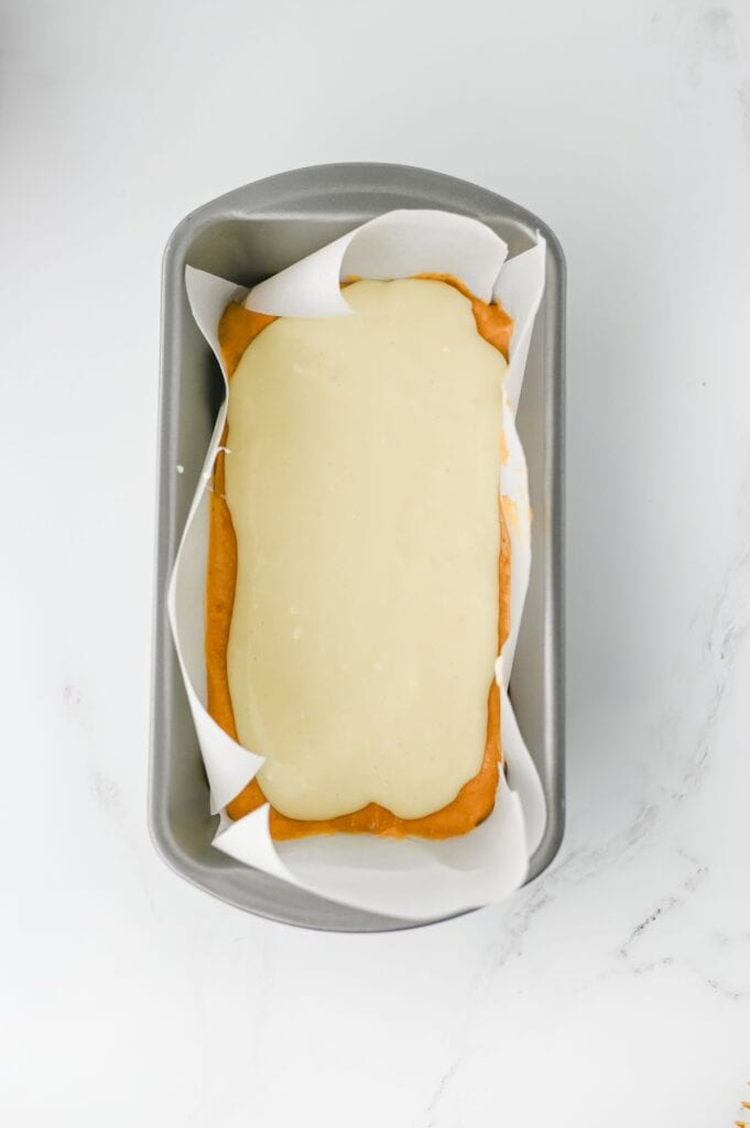 Pumpkin Cream Cheese Bread, in process, cream cheese layered on batter in loaf pan.