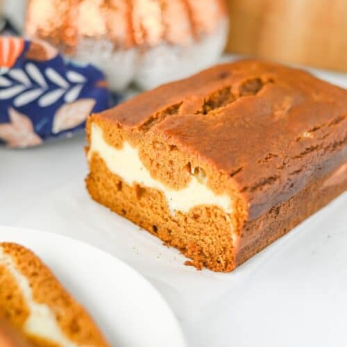 Pieces of Pumpkin Cream Cheese Bread oaf and slices on white plate.