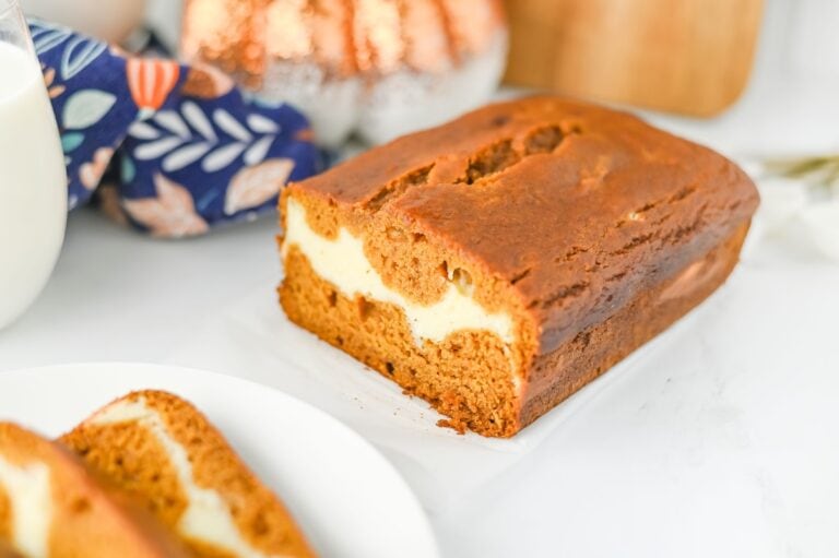 Pieces of Pumpkin Cream Cheese Bread oaf and slices on white plate.