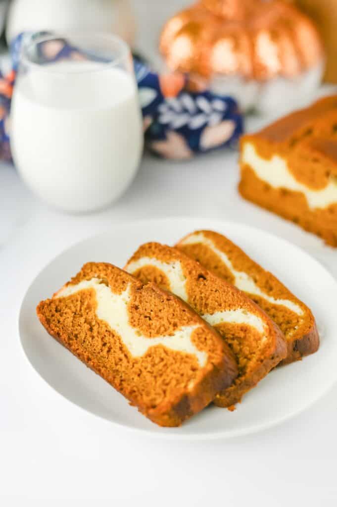 Pieces of Pumpkin Cream Cheese Bread on white plate with glass of milk.