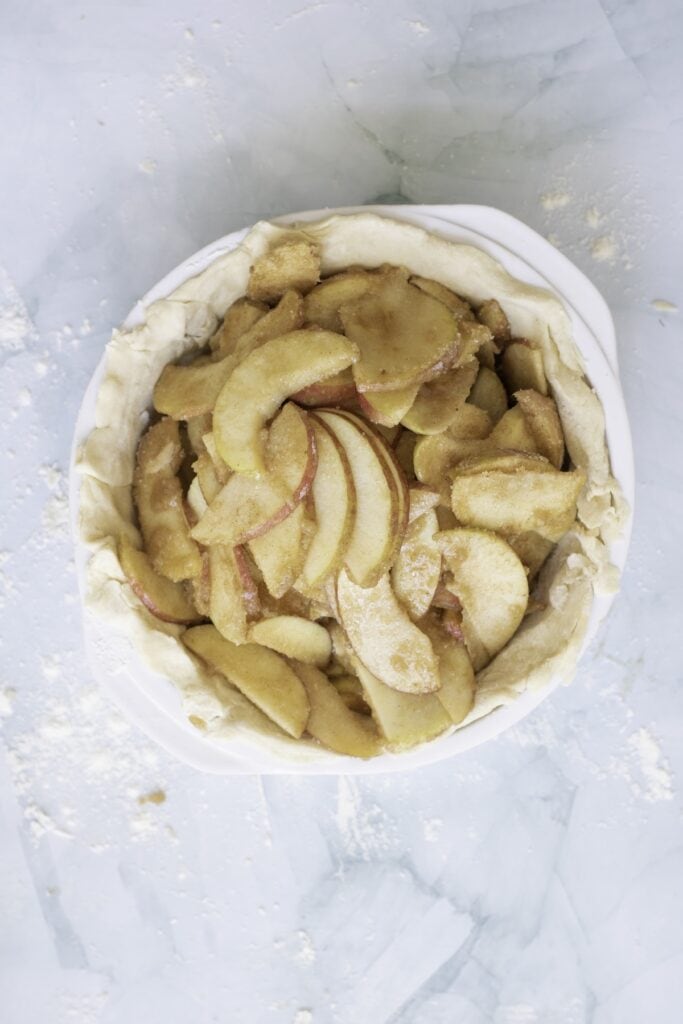 Double-Crust Honeycrisp Apple Pie, in process, apple mixture added to dough in baking dish.