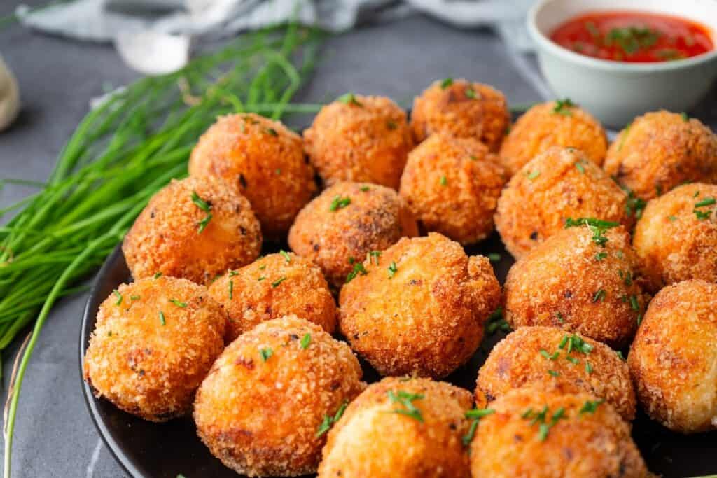 Golden Parmesan Herb Potato Bites, close-up on black plate.