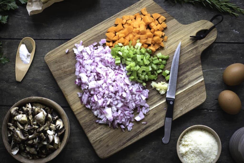 Homemade Herb and Vegetable Stuffing, in process, shopped vegetables in wooden cutting board.