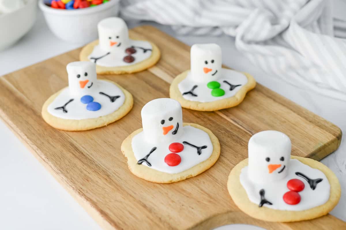 Melted Snowman Cookies on wooden cutting board.